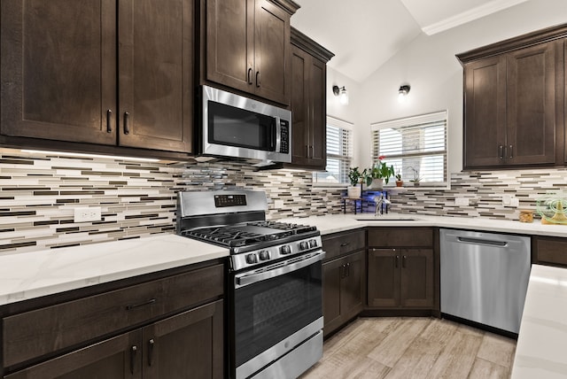 kitchen featuring decorative backsplash, dark brown cabinetry, appliances with stainless steel finishes, and lofted ceiling