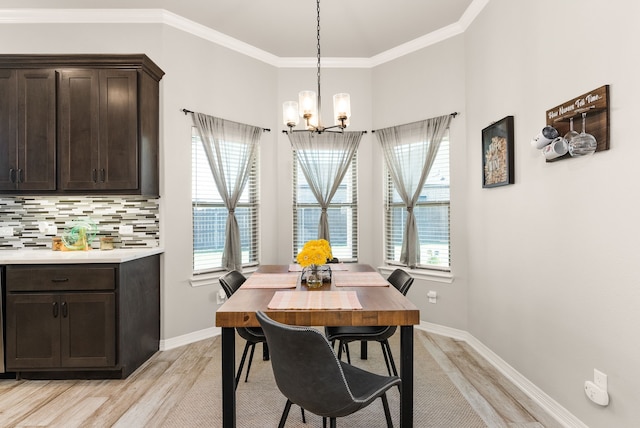 dining area featuring a notable chandelier, light hardwood / wood-style flooring, crown molding, and a wealth of natural light