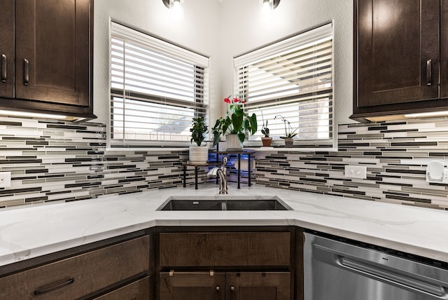 kitchen with light stone countertops, sink, stainless steel dishwasher, and dark brown cabinets