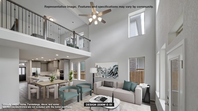 living room with light hardwood / wood-style floors, ceiling fan, and a towering ceiling