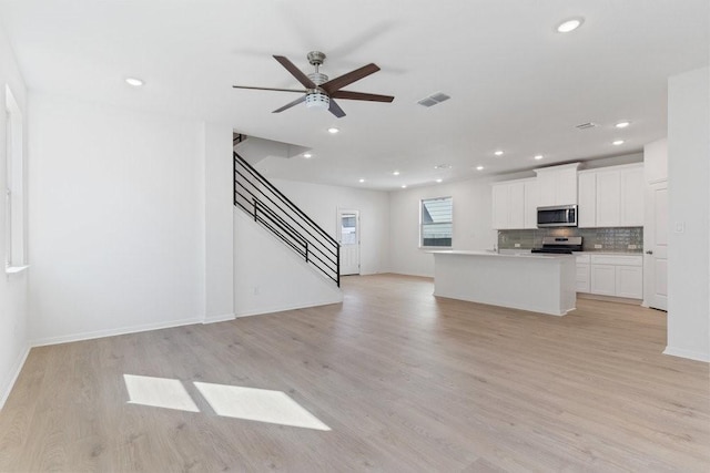 unfurnished living room featuring ceiling fan and light wood-type flooring