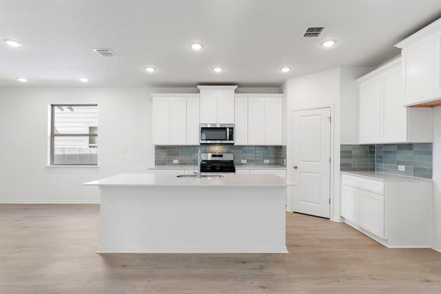 kitchen featuring white cabinetry, stainless steel appliances, and a kitchen island with sink