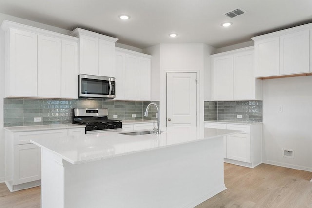 kitchen featuring white cabinets, appliances with stainless steel finishes, and a center island with sink