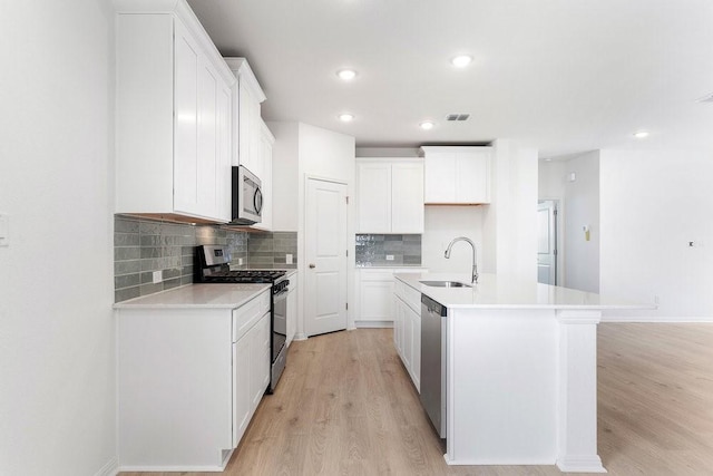 kitchen with a kitchen island with sink, white cabinetry, and stainless steel appliances