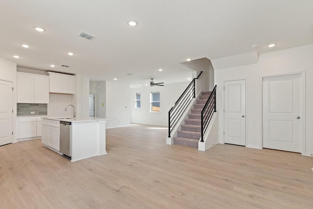 kitchen with dishwasher, white cabinetry, sink, a kitchen island with sink, and light hardwood / wood-style flooring