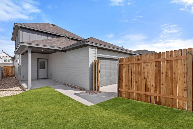 back of house featuring a garage and a yard