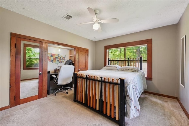 carpeted bedroom with ceiling fan, multiple windows, and a textured ceiling