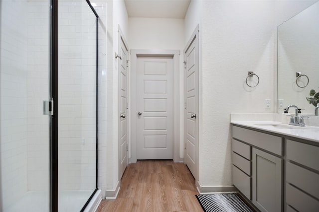 bathroom featuring a shower with door, wood-type flooring, and vanity