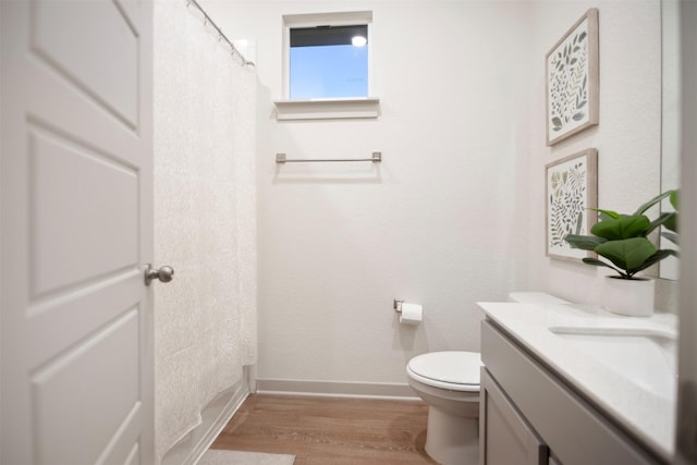 bathroom with hardwood / wood-style floors, toilet, vanity, and a shower with curtain