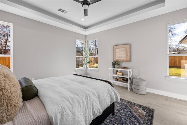 bedroom featuring ceiling fan, hardwood / wood-style floors, and a raised ceiling