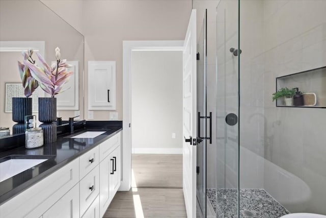 6003 Libyan Dr, Austin, TX 78745 - bathroom featuring double vanity, a stall shower, baseboards, and wood finished floors