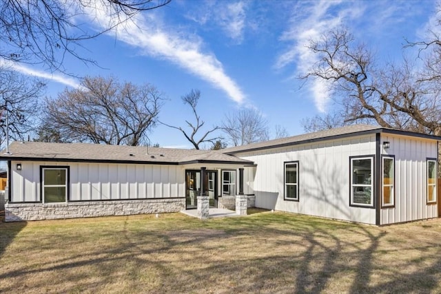 6003 Libyan Dr, Austin, TX 78745 - back of house featuring board and batten siding, stone siding, a lawn, and a shingled roof