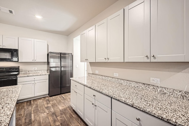 kitchen with stainless steel refrigerator, white cabinetry, light stone countertops, and electric range