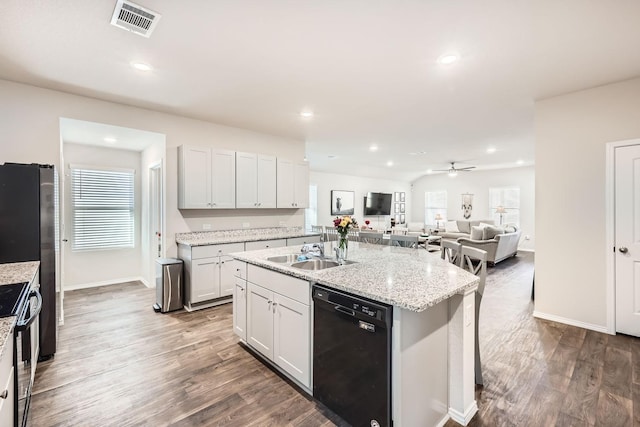 kitchen with sink, range, black dishwasher, an island with sink, and white cabinets