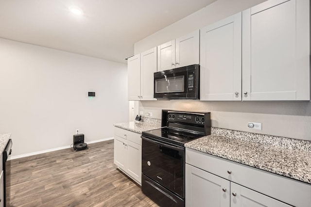 kitchen featuring white cabinetry, light stone counters, black appliances, and light hardwood / wood-style floors