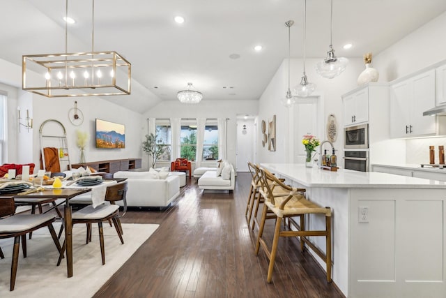 kitchen featuring white cabinets, stainless steel oven, built in microwave, and pendant lighting