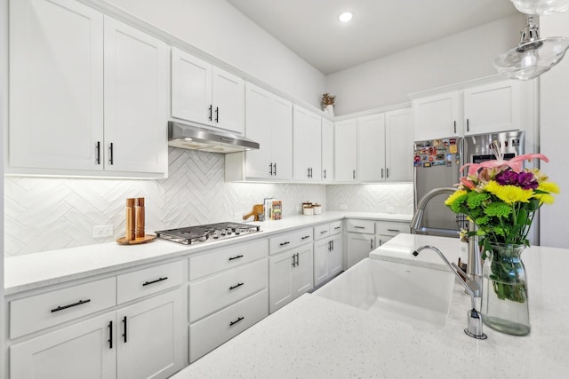 kitchen with white cabinetry, decorative backsplash, sink, stainless steel appliances, and light stone counters