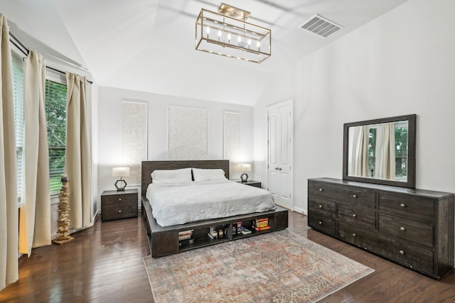 bedroom with an inviting chandelier, dark hardwood / wood-style floors, and lofted ceiling