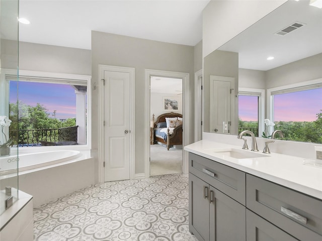 ensuite bathroom featuring visible vents, a healthy amount of sunlight, vanity, and a garden tub