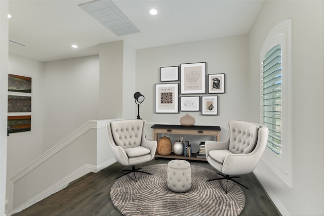 living area with recessed lighting, wood finished floors, baseboards, and an upstairs landing