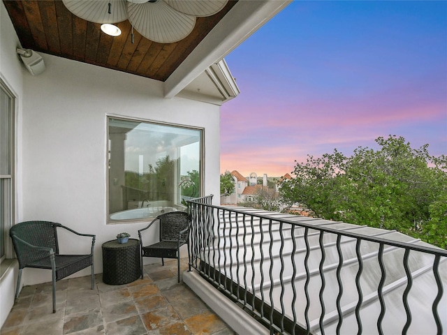 balcony at dusk featuring ceiling fan