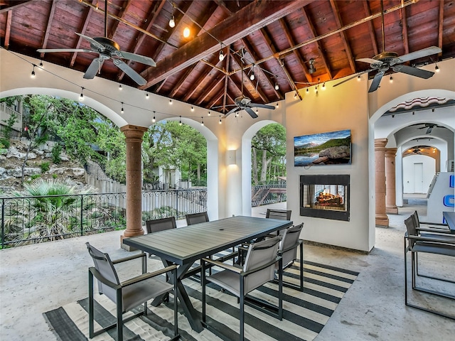 view of patio / terrace with a multi sided fireplace, outdoor dining area, ceiling fan, and fence