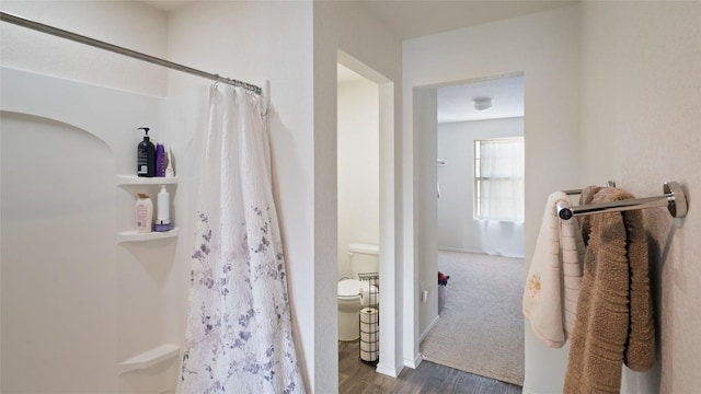 bathroom with hardwood / wood-style flooring, toilet, and a shower with shower curtain