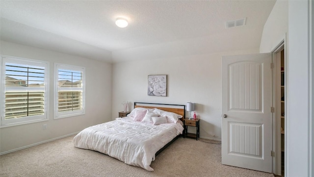 bedroom with light colored carpet and a textured ceiling