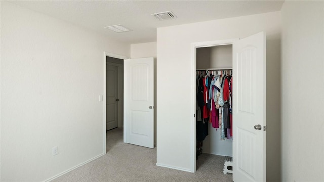 unfurnished bedroom featuring a walk in closet, light colored carpet, and a closet