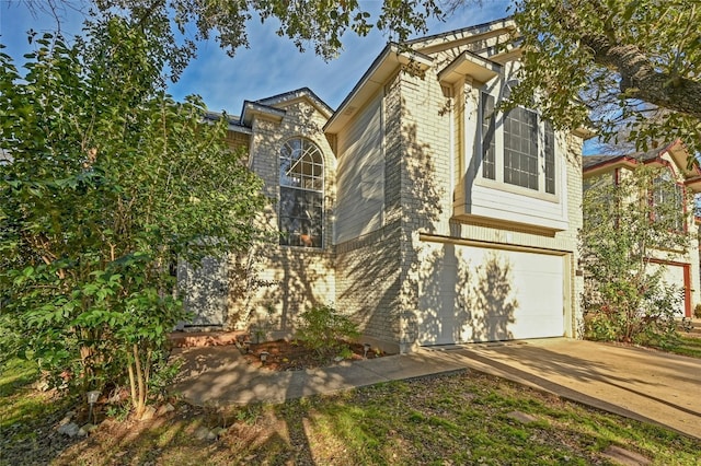 view of side of home featuring an attached garage, brick siding, and driveway