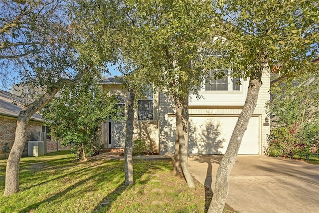 view of property hidden behind natural elements with a garage and a front yard