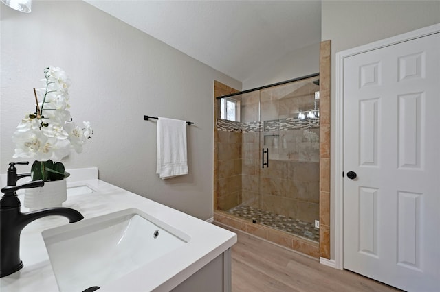 bathroom with hardwood / wood-style floors, a shower with shower door, lofted ceiling, and vanity