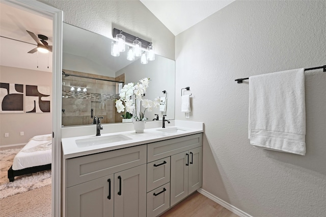 bathroom featuring lofted ceiling, vanity, hardwood / wood-style flooring, walk in shower, and ceiling fan