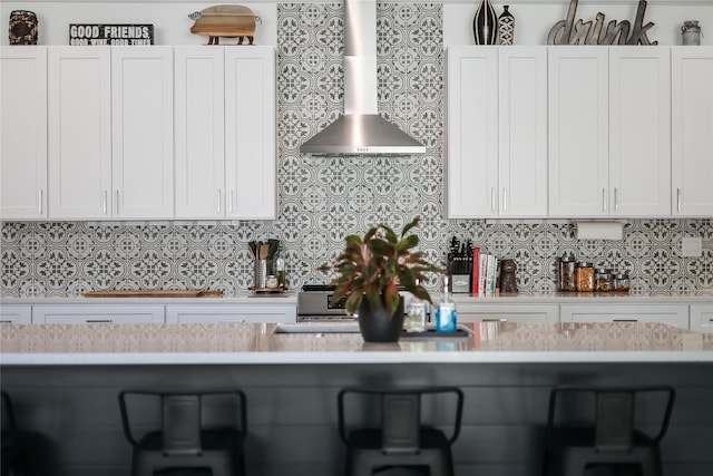 kitchen featuring white cabinetry, wall chimney exhaust hood, and tasteful backsplash