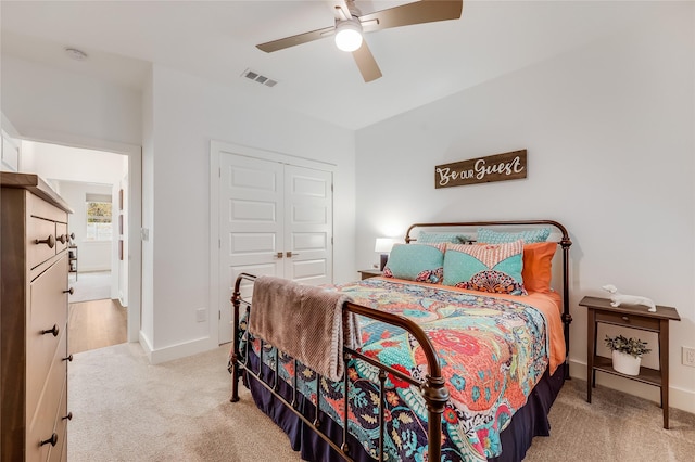 bedroom with a closet, ceiling fan, and light colored carpet