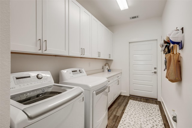 clothes washing area with independent washer and dryer, cabinets, and dark wood-type flooring