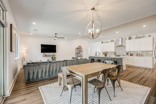 dining space with ceiling fan with notable chandelier and light hardwood / wood-style flooring