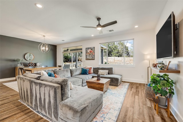 living room with hardwood / wood-style flooring and ceiling fan with notable chandelier