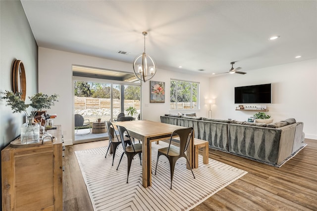 dining space with light hardwood / wood-style floors and ceiling fan with notable chandelier