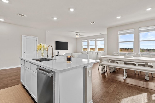 kitchen featuring dishwasher, wood-type flooring, white cabinetry, sink, and a center island with sink