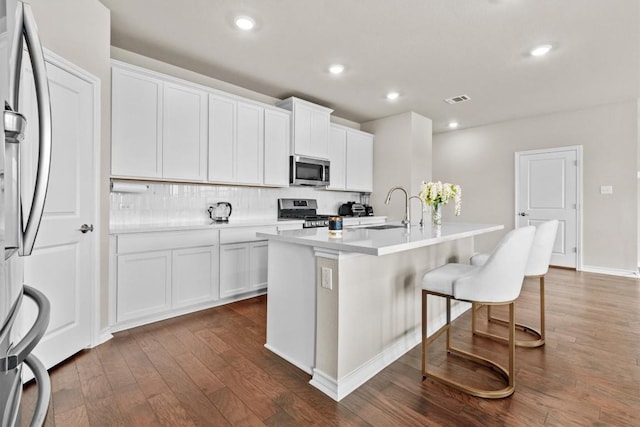 488 Pepperbark Loop, Buda, TX 78610 - kitchen with appliances with stainless steel finishes, a sink, dark wood finished floors, decorative backsplash, and a breakfast bar area