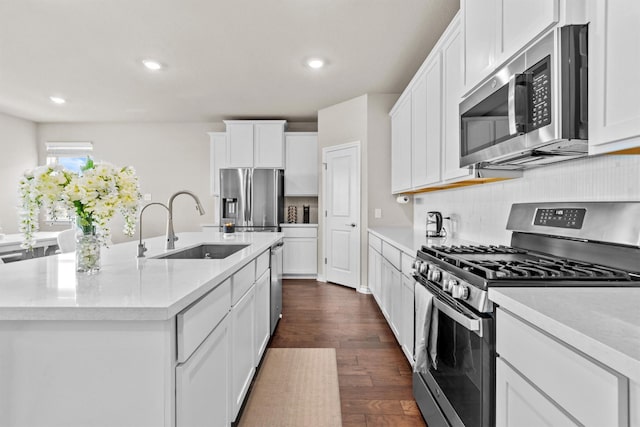 kitchen with sink, white cabinets, stainless steel appliances, and an island with sink