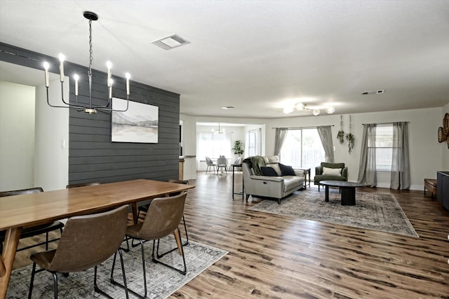 dining area featuring wooden walls, hardwood / wood-style floors, and a chandelier