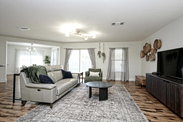 living room with hardwood / wood-style floors, plenty of natural light, and a notable chandelier