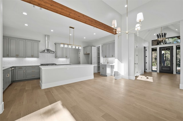 kitchen featuring wall chimney exhaust hood, a center island, and gray cabinetry