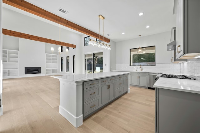 kitchen featuring pendant lighting, dishwasher, a center island, tasteful backsplash, and light stone counters