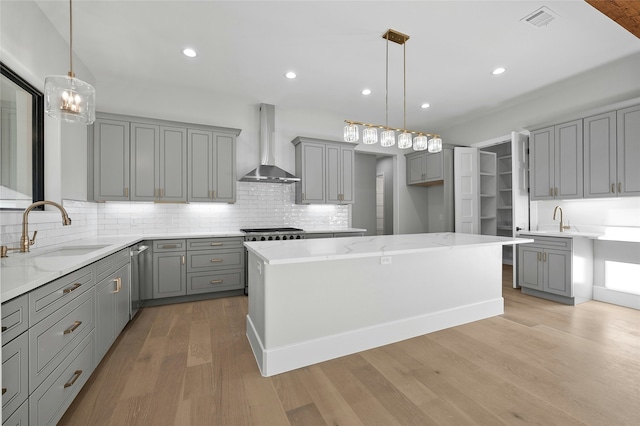 kitchen featuring a center island, sink, gray cabinetry, and wall chimney exhaust hood