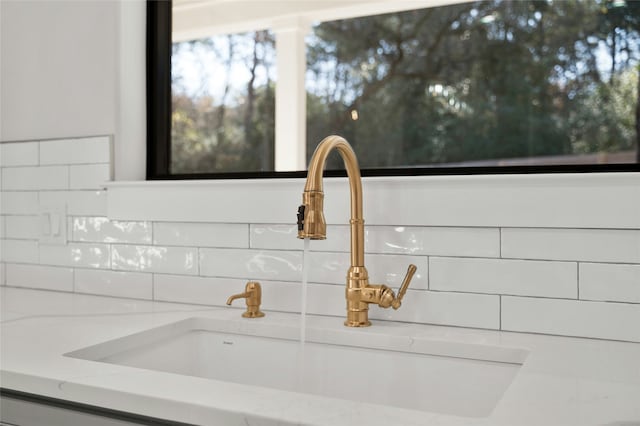 room details with sink, white cabinetry, and light stone countertops