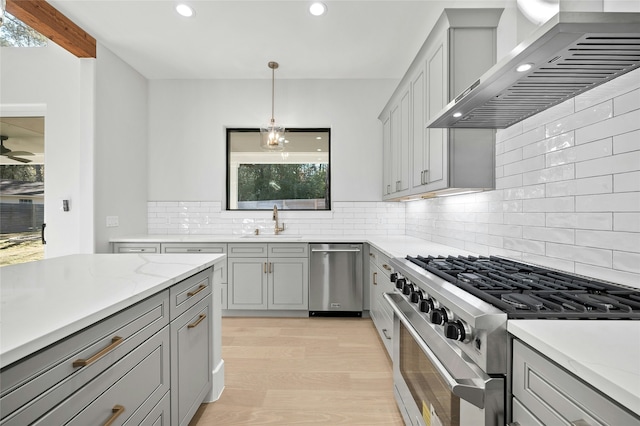 kitchen featuring decorative light fixtures, wall chimney range hood, decorative backsplash, and stainless steel appliances