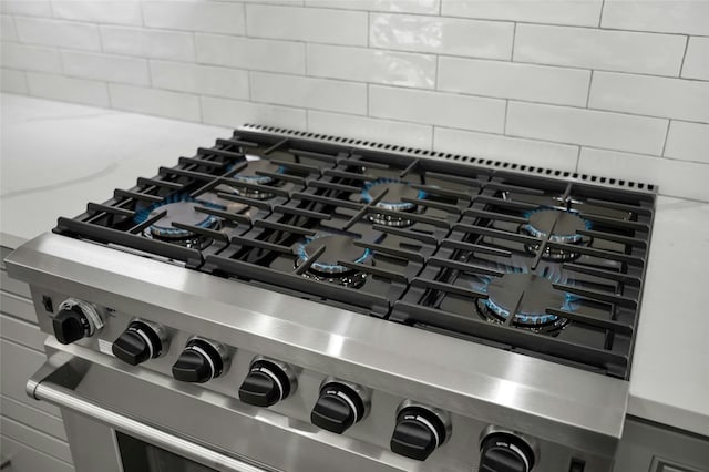 room details featuring stainless steel gas range oven, tasteful backsplash, and cooktop